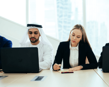Professionals discussing work on a laptop, highlighting fast Arabic typing services for timely and reliable results.