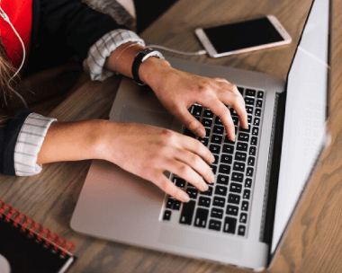 A woman working on a laptop, ideal for word-to-word transcription and typing services with attention to detail.
